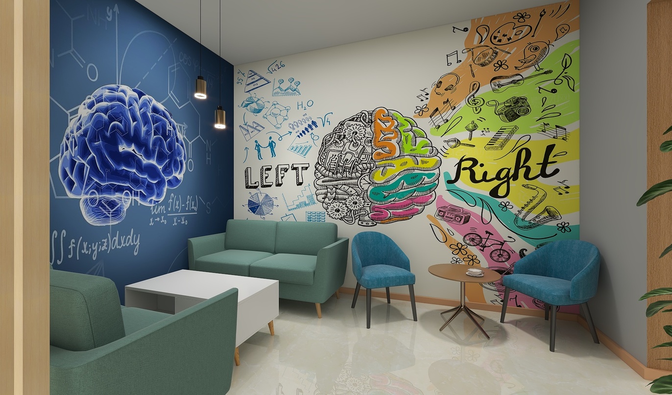 这是一幅色彩斑斓的办公室休息区场景。左侧的墙壁上画着一个大脑，旁边写着“LEFT”，下面写着“RIGHT”。墙壁中间部分还写着“PSYCHOLOGLY”。墙壁右侧是绿色的沙发和两把椅子。沙发上还放着一个白色茶几。整个场景的设计非常有艺术感，同时也充满了活力。